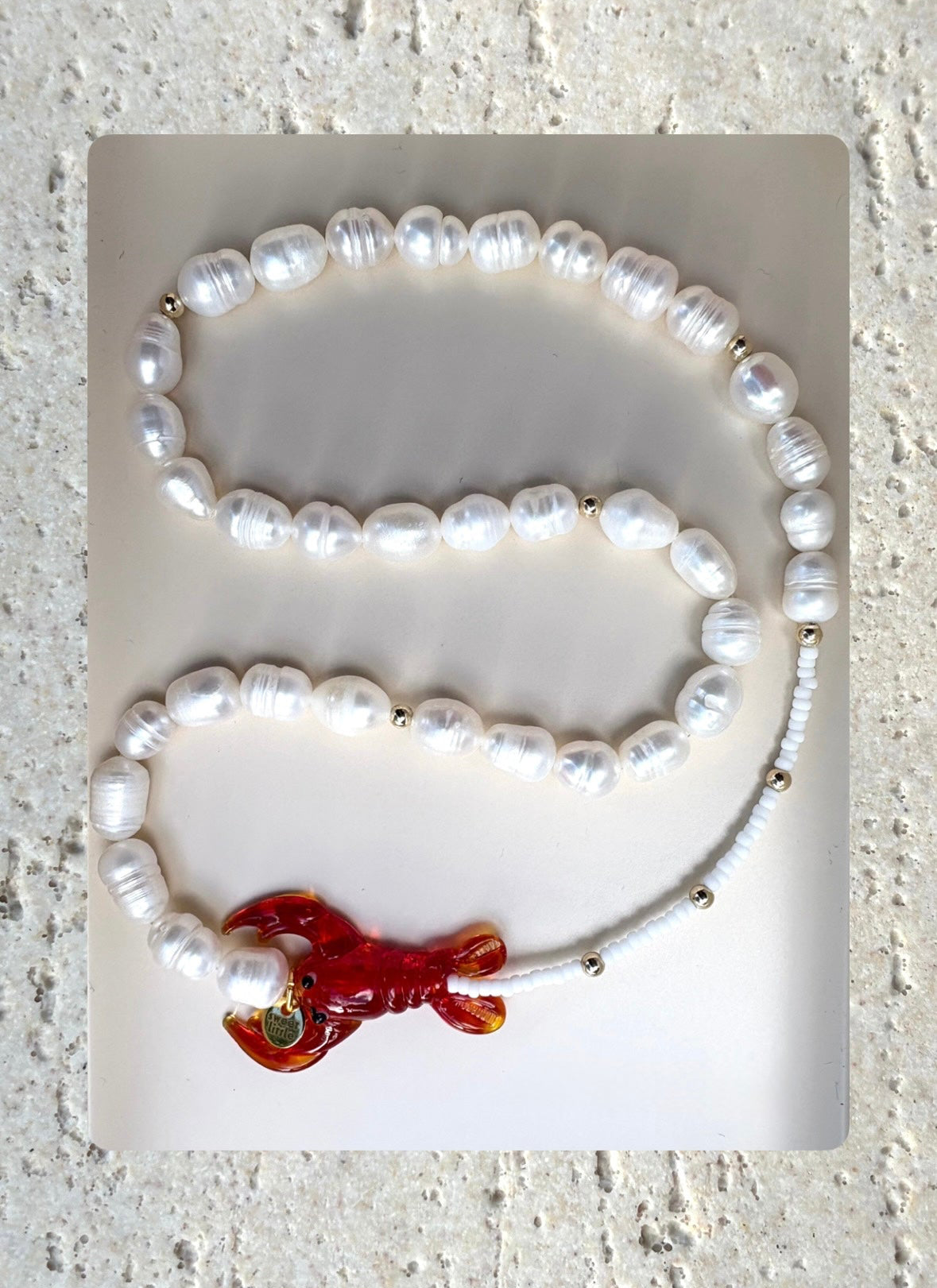pearl necklace with a red lobster charm.