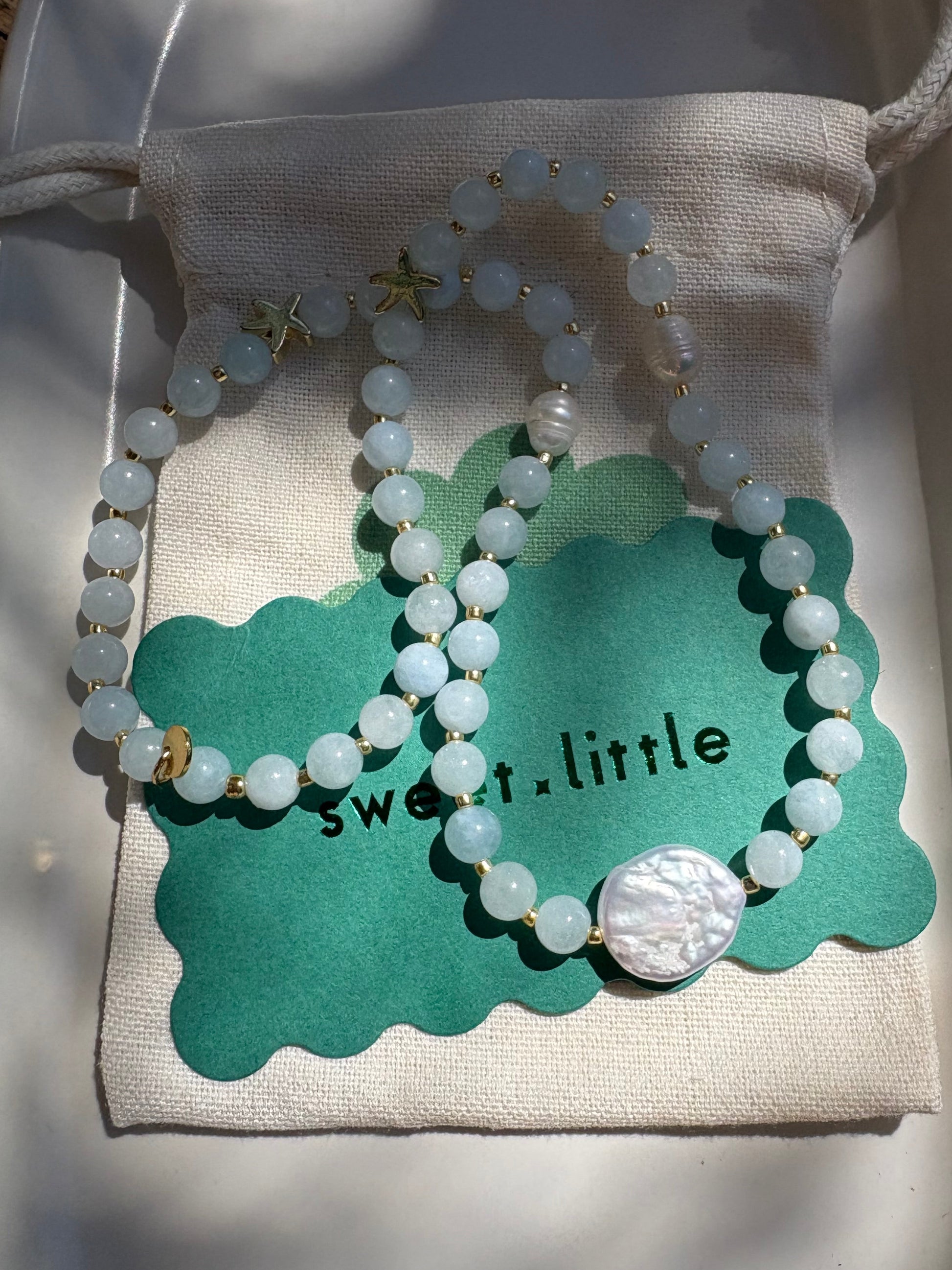 Set of beaded bracelets on a decorative card with 'sweet little' text, placed on a textured surface.