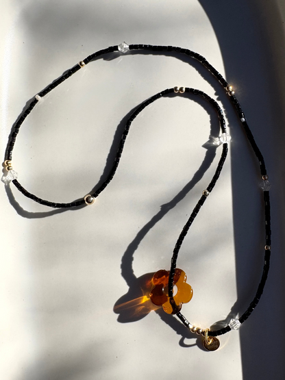 Beaded necklace with a flower pendant on a light background